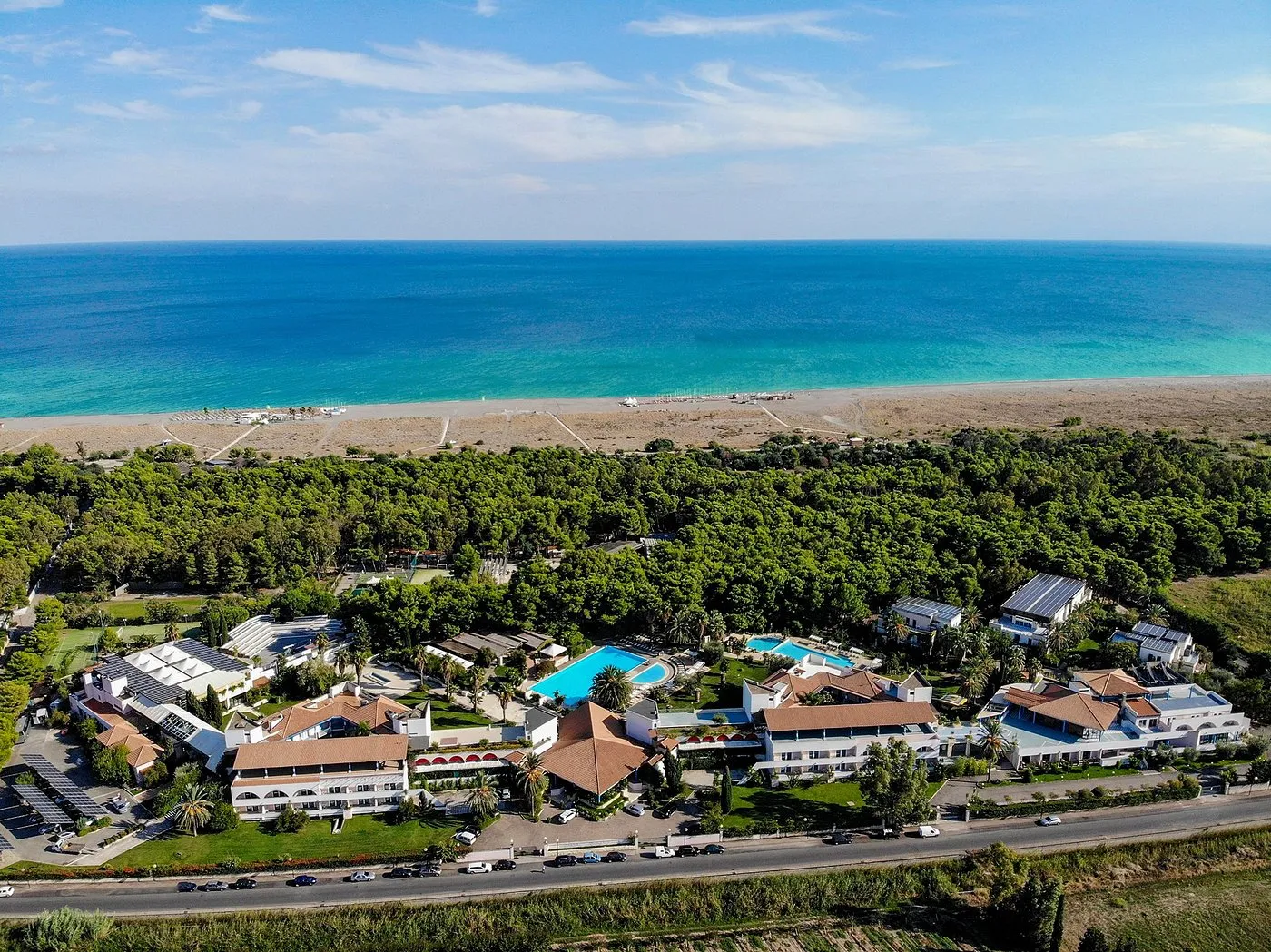 Vista aerea del resort immerso nel verde con piscine e spiaggia sul mare turchese