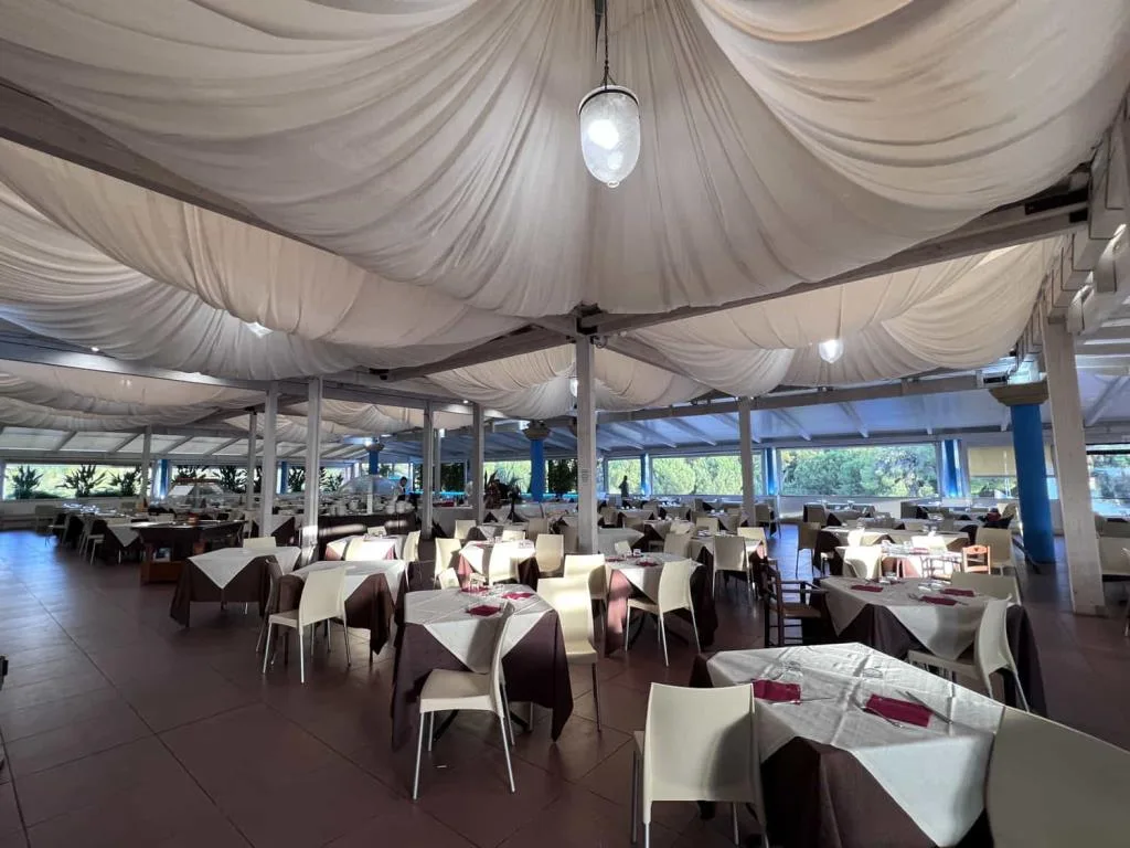 Sala ristorante interna con soffitto in tessuto drappeggiato bianco e tavoli apparecchiati