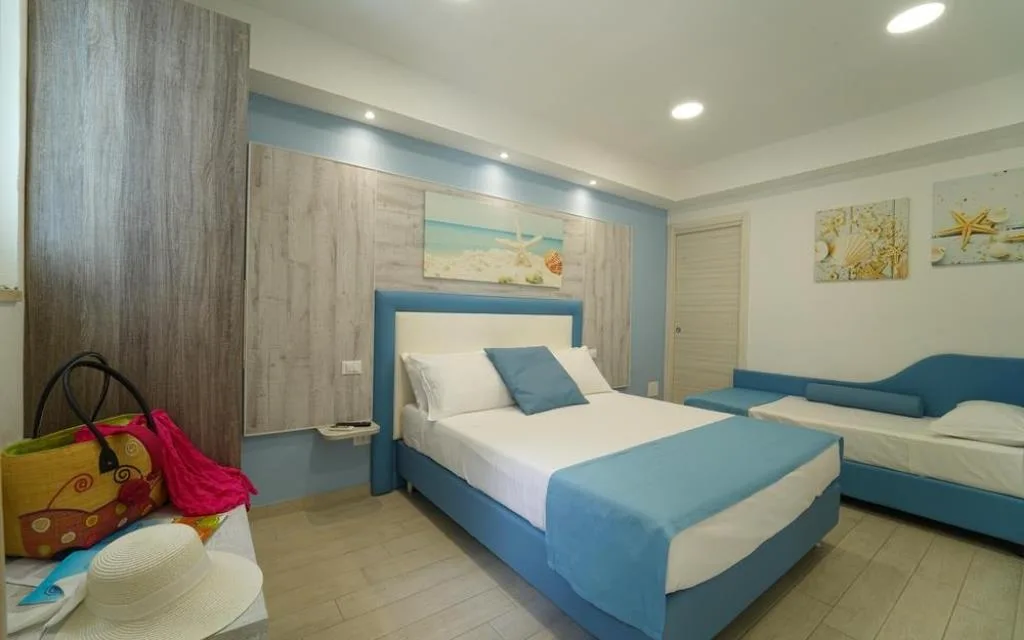 Camera luminosa con letto matrimoniale, divano letto e arredi in stile mare