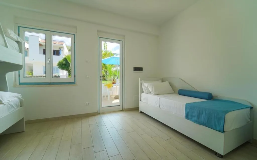 Camera con letto singolo e letto a castello e uscita sul terrazzo con ombrellone