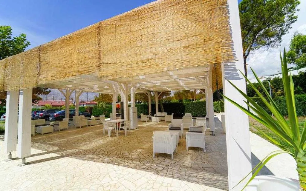Area lounge esterna con pergolato in canne, poltrone e tavolini in vimini