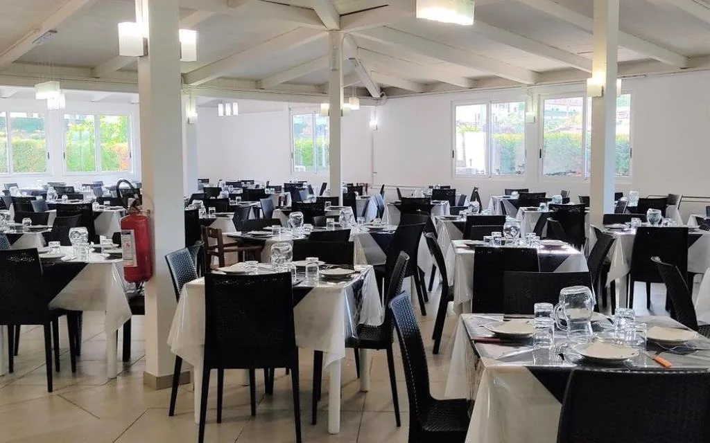 Sala ristorante interna con tavoli apparecchiati e sedie scure