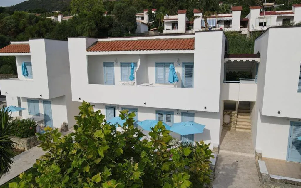 Palazzine bianche con tetti in tegole, balconi e ombrelloni azzurri