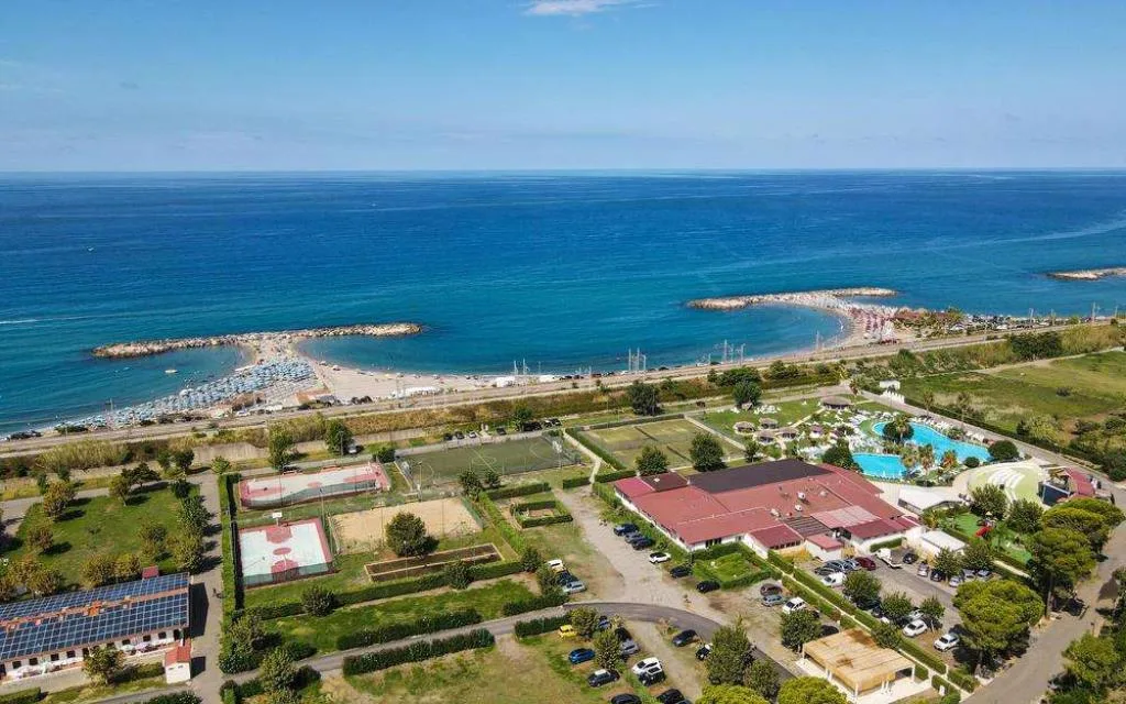 Vista aerea del resort con piscina e campi sportivi affacciati sul mare