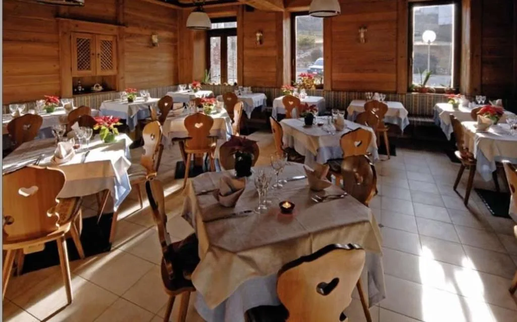 Sala ristorante rustica con rivestimenti in legno e tavoli apparecchiati