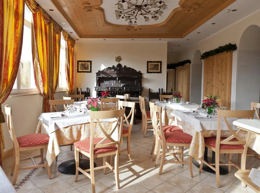 Sala da pranzo luminosa con soffitto in legno e credenza antica