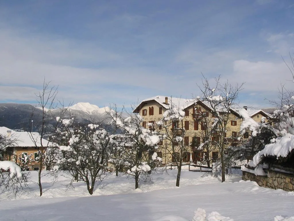 Hotel immerso nella neve tra alberi con vette innevate all'orizzonte