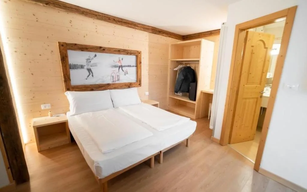 Camera matrimoniale con pareti in legno chiaro e guardaroba aperto