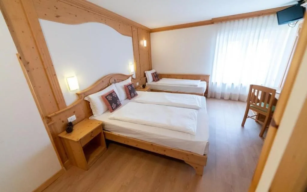 Camera tripla con arredo in legno e ampia finestra