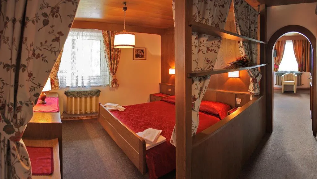 Camera matrimoniale con letto a baldacchino, tende floreali e copriletto rosso