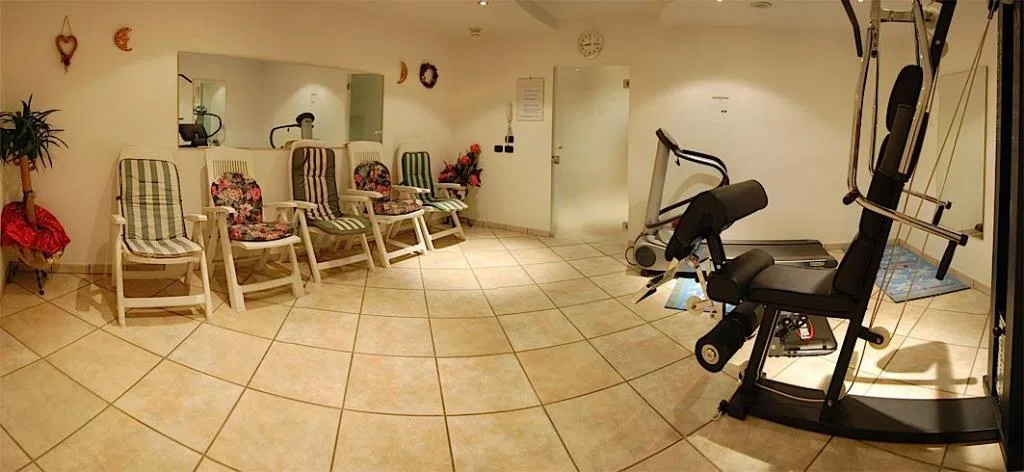 Zona relax e fitness con lettini imbottiti e attrezzature da palestra