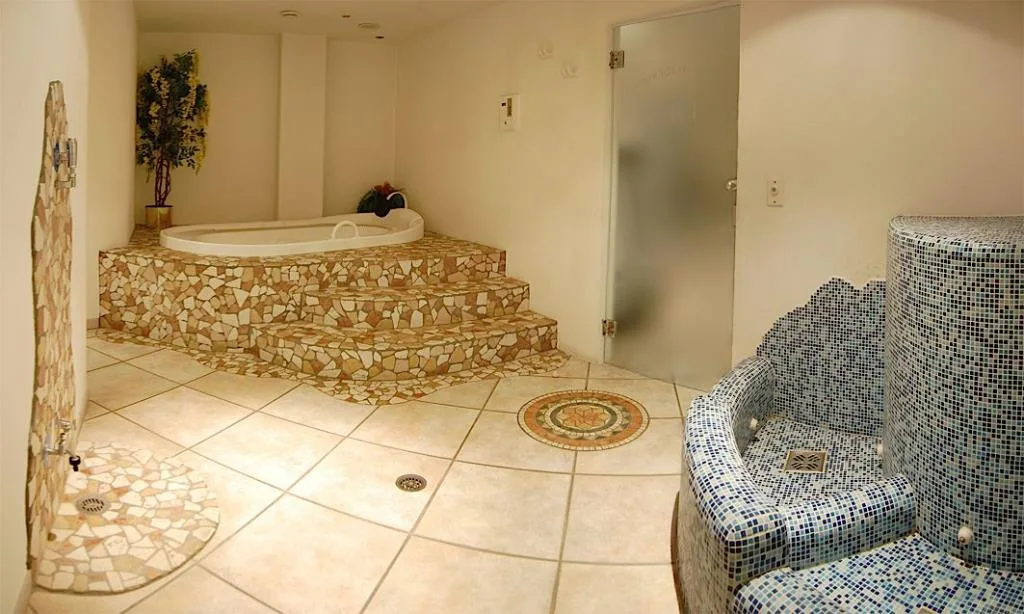 Area wellness con vasca idromassaggio, rivestimenti in mosaico e sauna