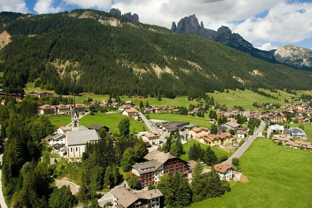 Veduta aerea del paese di montagna con chiesa, hotel e Dolomiti sullo sfondo