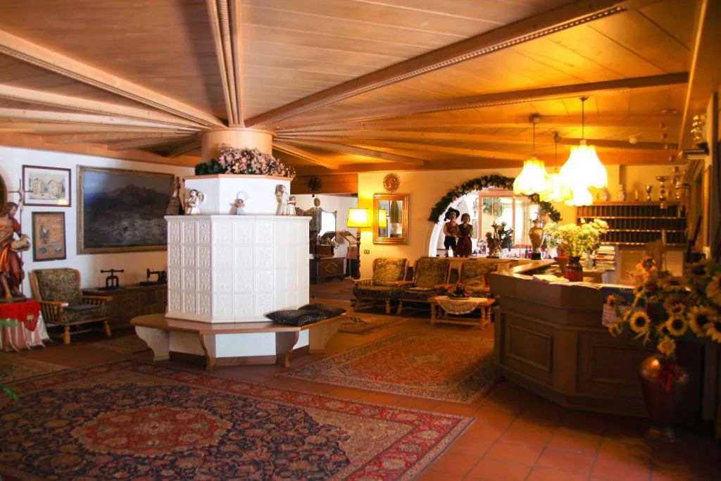 Hall dell'hotel con stufa in maiolica bianca, poltrone, tappeti e reception in legno