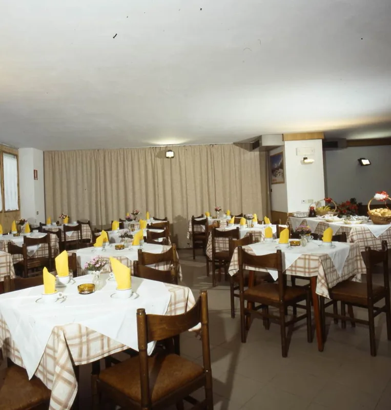 Sala da pranzo con tavoli apparecchiati con tovaglie a quadri e tovaglioli gialli