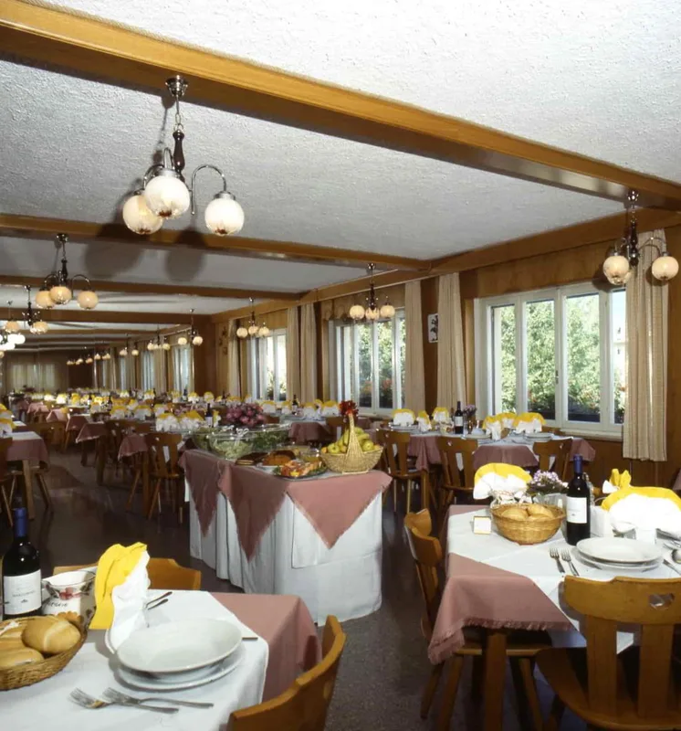 Ampia sala ristorante con tavoli apparecchiati, buffet di frutta e lampadari in legno