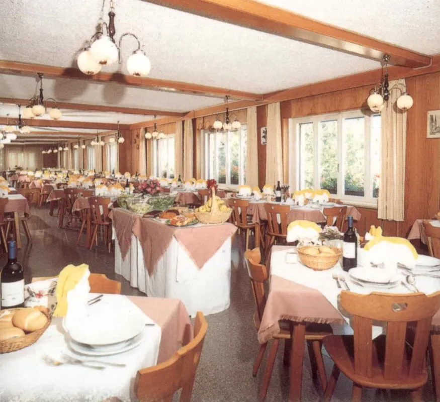 Sala ristorante luminosa con tavoli apparecchiati, buffet centrale e grandi finestre