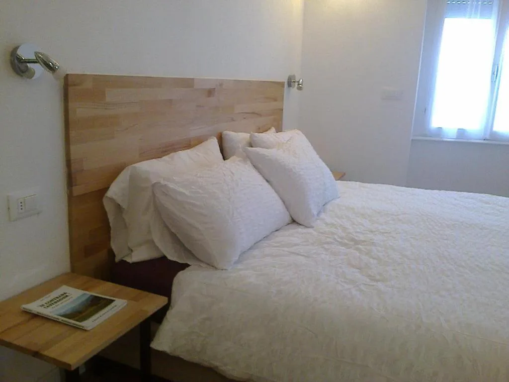 Camera con letto matrimoniale, testiera in legno e cuscini bianchi