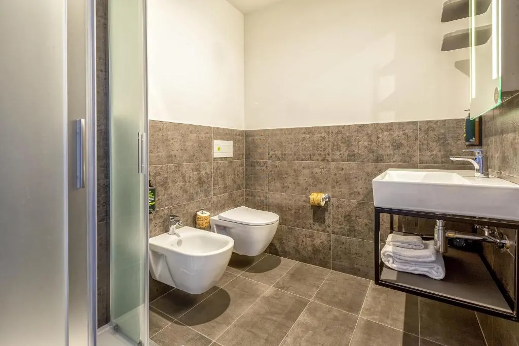 Bagno moderno con doccia, WC, bidet e lavabo su struttura in metallo