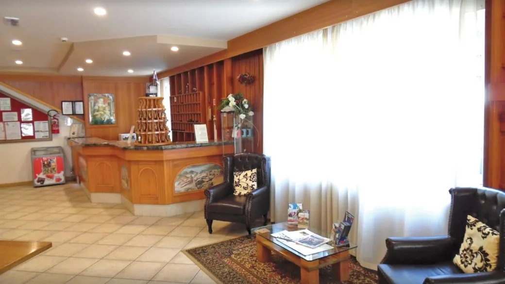 Reception dell'hotel con bancone in legno, poltrone in pelle e ampia vetrata