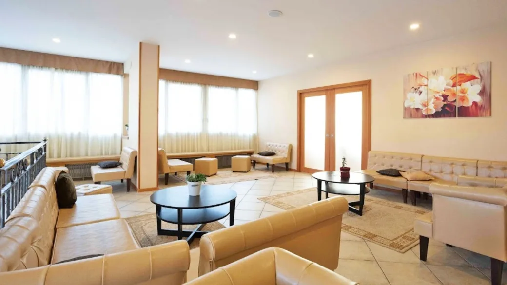 Ampia hall con divani in pelle beige, tavolini e arredamento luminoso