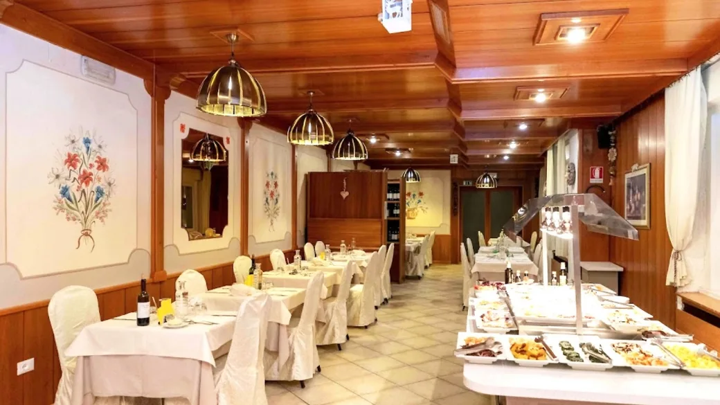 Sala ristorante con soffitto in legno, tavoli apparecchiati e ricco buffet