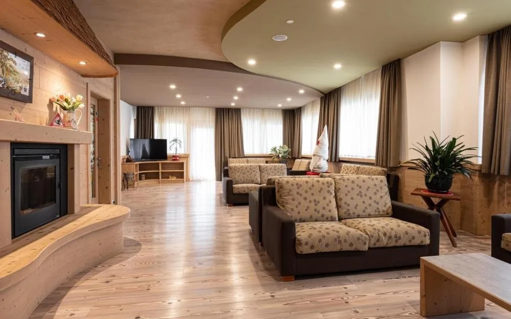 Ampia hall lounge con camino, divani a fiori e pavimento in legno chiaro