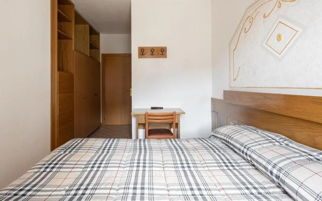 Camera con letto matrimoniale, armadio in legno e scrivania vicino all'ingresso
