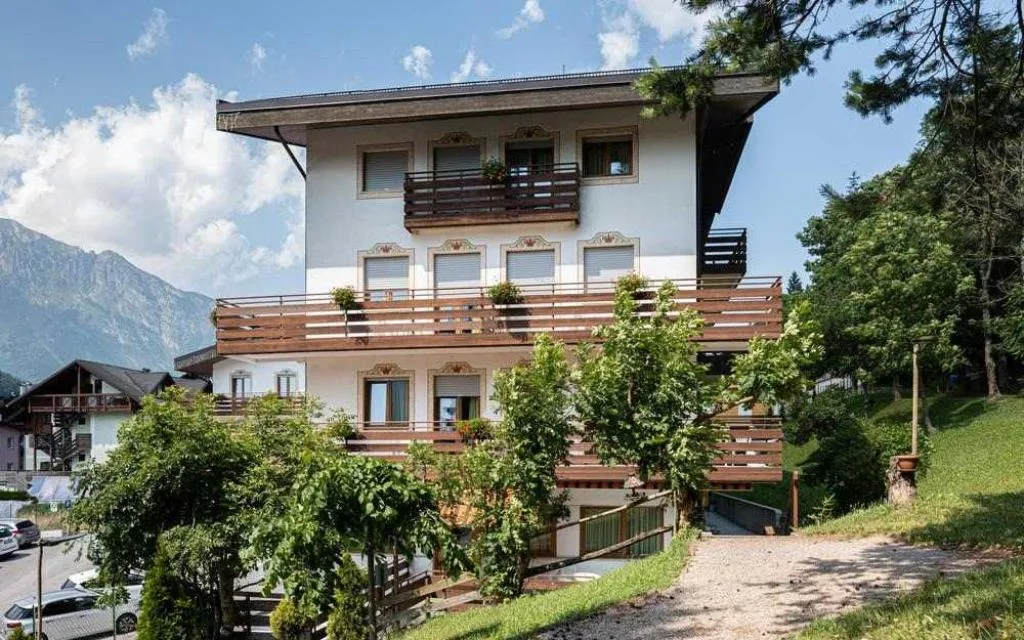 Facciata estiva di edificio alpino con balconi in legno e vista sulle montagne