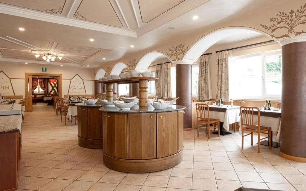 Sala ristorante elegante con buffet centrale in legno, colonne e soffitto decorato